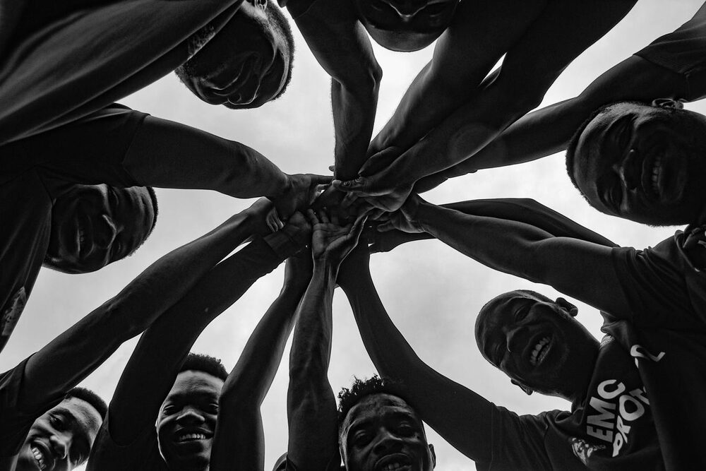 A team huddle of hands and faces joined together, representing organisational cooperation and collective resilience